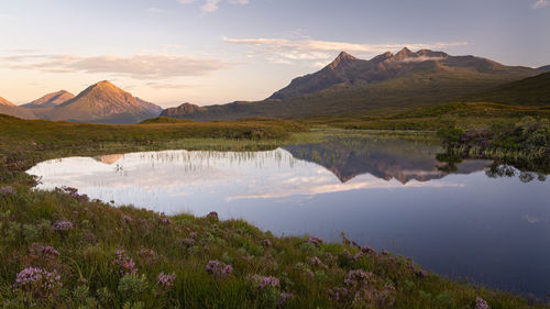 Panoramic view of cuillin mountain range reflected in calm water on isle of skye, scotland