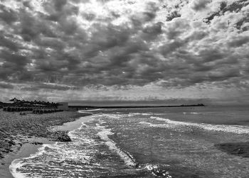 Scenic view of beach against cloudy sky