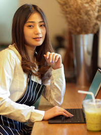 Young woman using mobile phone while sitting on table