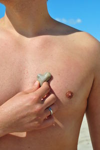 Midsection of shirtless woman standing on beach