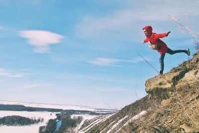 Woman balancing on rock against sky