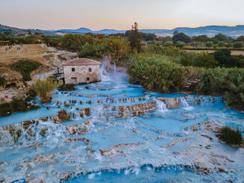 Water flowing through rocks on land against sky