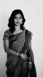 Portrait of smiling young woman standing against white background