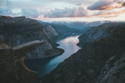 Man standing on cliff against sky during sunset