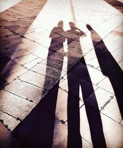 High angle view of couple shadow on tiled floor