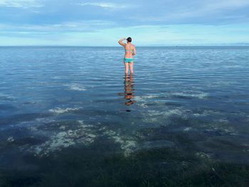 Rear view of woman standing in sea against sky