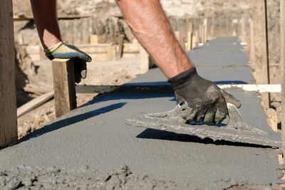 Construction worker spreading concrete mix of house foundation