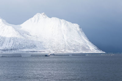 Scenic view of sea by snowcapped mountain against sky