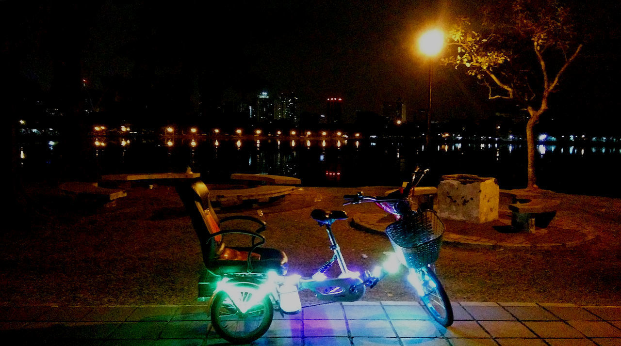 ILLUMINATED STREET LIGHT BY CITY AT NIGHT