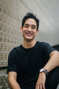 Portrait of smiling mid adult man sitting against wall