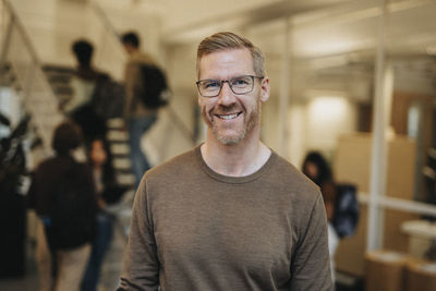 Portrait of smiling mature professor standing in university