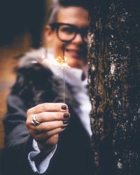 Portrait of young man holding sunglasses standing outdoors