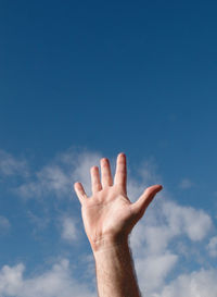 Low angle view of hand against blue sky