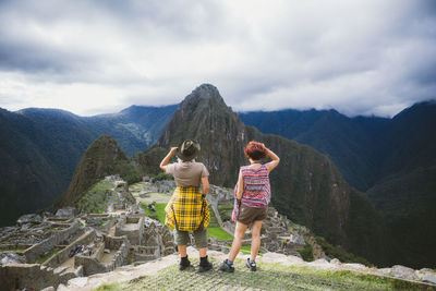 Rear view of woman standing on mountain against sky