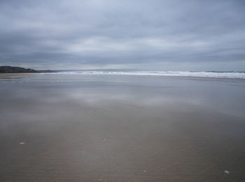 Scenic view of beach against cloudy sky