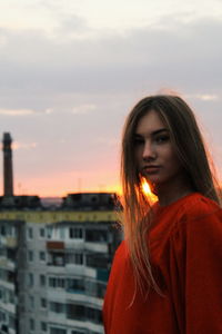 Portrait of beautiful woman standing against orange sky