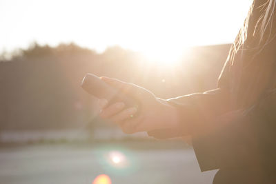 Close-up of woman hand against bright sun during sunset