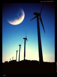 Low angle view of wind turbine against blue sky