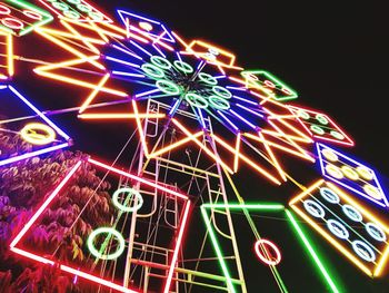 Low angle view of illuminated ferris wheel against sky at night