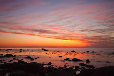 Scenic view of calm pebble beach at sunset