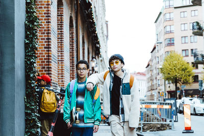 Multiracial male friends walking on footpath while hanging out in city