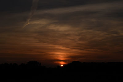 Scenic view of silhouette landscape against orange sky