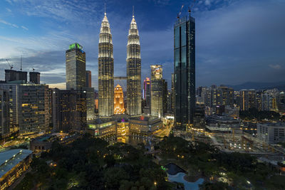 Aerial view of city lit up against cloudy sky