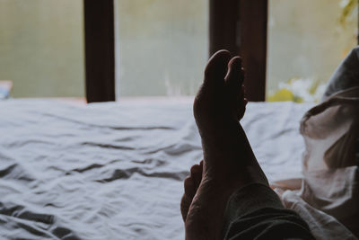 Low section of man relaxing on bed