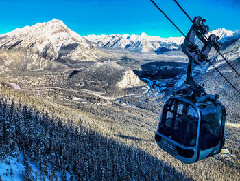 Overhead cable car on snowcapped mountains against blue sky