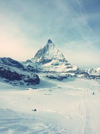 Scenic view of snow covered landscape by rocky mountains against sky