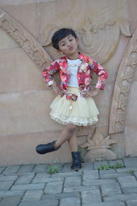 Portrait of smiling girl standing against wall