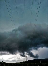 Low angle view of electricity pylon against storm clouds
