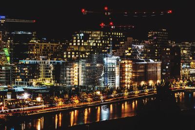 Illuminated buildings by river at night