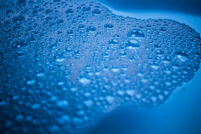 Close-up of water drops on blue surface