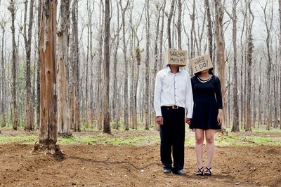 Couple wearing boxes with text while standing in forest