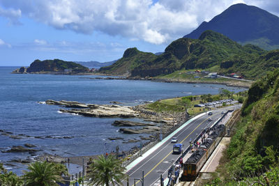 Scenic view of sea by mountains against sky