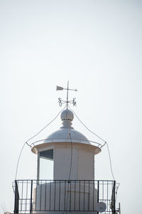 Low angle view of weather vane against building