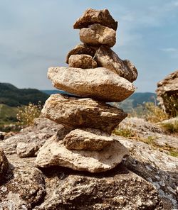 Stack of stones on rock against sky