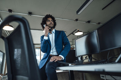 Young male professional talking on landline phone in office