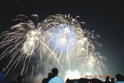 Low angle view of people watching firework display