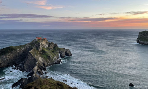 Scenic view of sea against sky at san juan de gaztelugatxe during sunrise