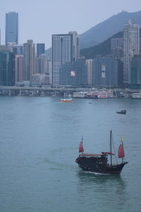 Ship sailing in sea against buildings in city