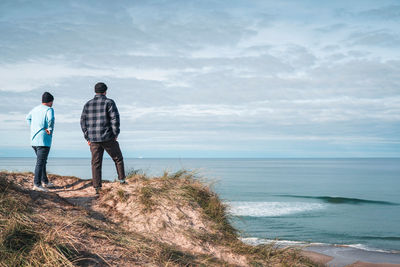 Rear view people standing against sea and sky