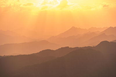 Scenic view of silhouette mountains against orange sky