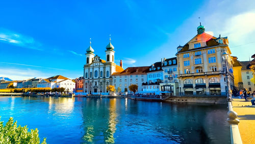 Canal amidst buildings against blue sky in city