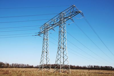 Low angle view of electricity pylon against clear sky