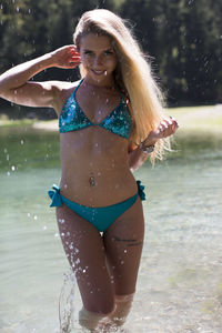 Portrait of young woman in bikini standing at swimming pool