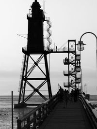 People on pier by sea against clear sky