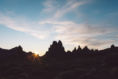 Panoramic view of silhouette rocks against sky during sunset