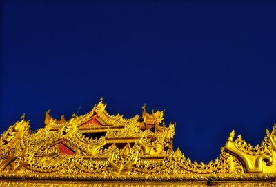 Low angle view of temple against building against clear blue sky